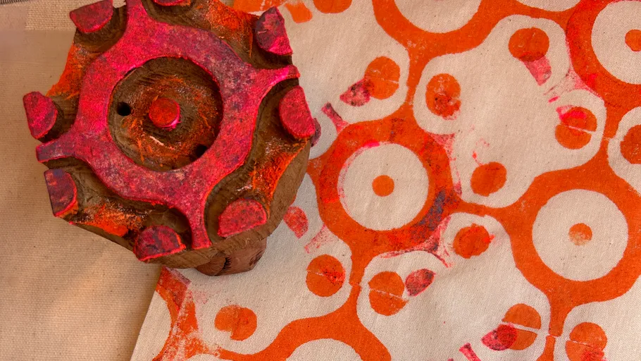 Wooden stamp on fabric with orange pattern.