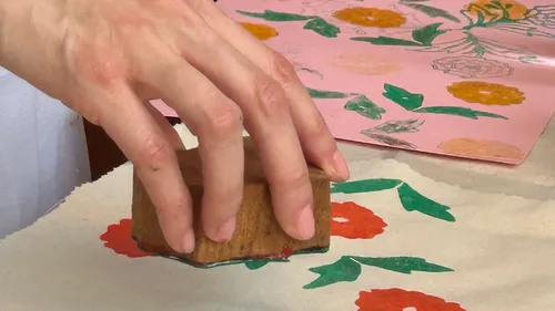 Hand using stamp on fabric with floral print.