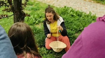 Woman teaching in a garden with a basket.