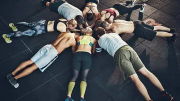 People planking in a circle, gym floor.