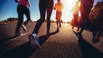 Group of people running on road, sunlight.