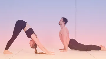 Zwei Personen machen Yoga-Posen drinnen.