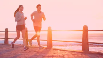 Zwei Personen joggen auf einem Küstenweg.