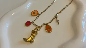Goldene Halskette mit Anhängern auf weißer Oberfläche.