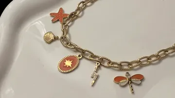 Armband mit verschiedenen Anhängern auf Teller.