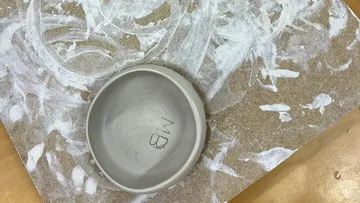 Tonschale auf strukturierter Oberfläche mit Initialen.