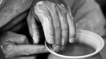 Hands shaping pottery on a wheel.