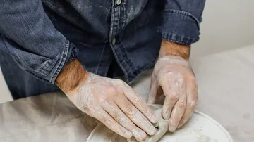 Person molding clay on a pottery wheel.