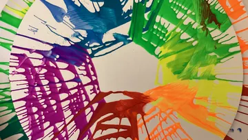 Colorful paint splatter on round canvas.