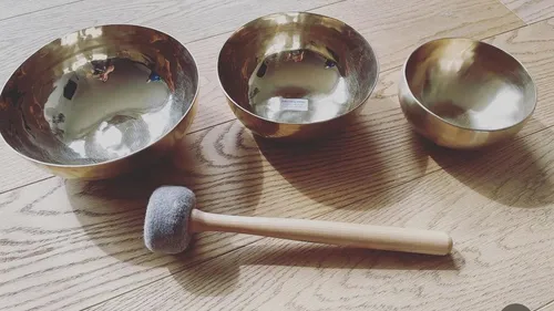 Three singing bowls and a mallet on wood.