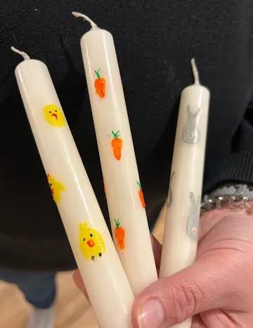 Hand hält verzierte Kerzen mit Tieren.