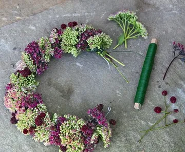Blumenkranz mit Werkzeugen auf Steinoberfläche.