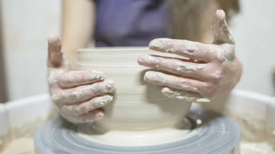 Hands shaping clay on a pottery wheel.
