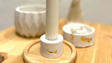 Candleholder with gold accents on wooden table.