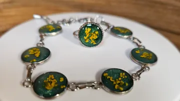 Armband mit gelben Blumen auf grünen Steinen.