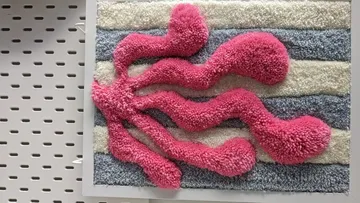 Colorful textured wall art with pink shapes.