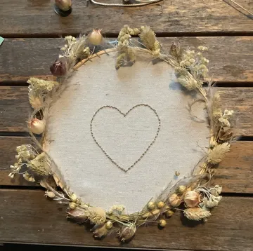 Heart-embroidered fabric with dried flower wreath.