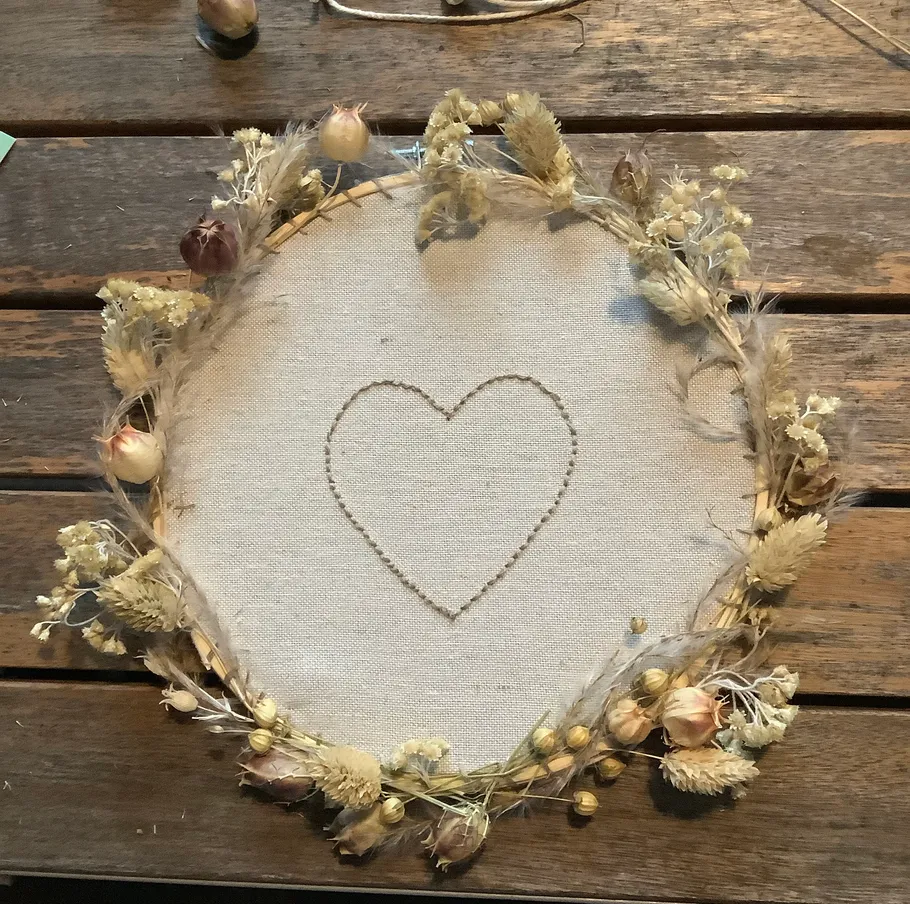 Heart-embroidered fabric with dried flower wreath.