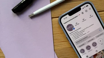 Telefon auf Tisch mit Stift und Papier.