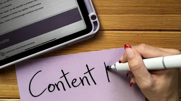 Hand schreibt 'Content' neben einem Tablet.