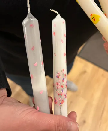 Hand holding decorated candles with flower design.