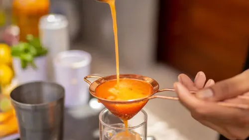 Flüssigkeit durch feines Sieb ins Glas gefiltert.