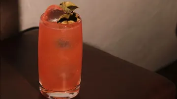 Roter Cocktail mit Eis und Blättern, Tischplatte.