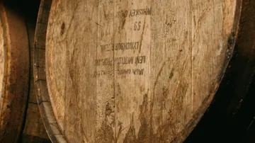 Wooden barrels with stamped text in dim light.