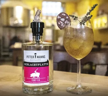 Schlachtplatte Gin-Flasche neben einem Cocktailglas.