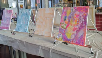 Abstract paintings displayed on easels in a cafe.