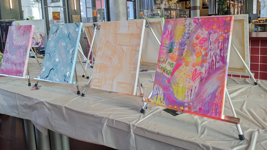 Abstract paintings displayed on easels in a cafe.