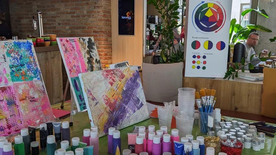 Art supplies on table with colorful paintings.