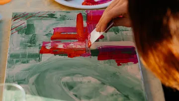 Hand painting abstract artwork with a spatula.