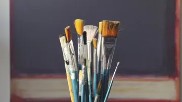 Paintbrushes in front of a canvas.