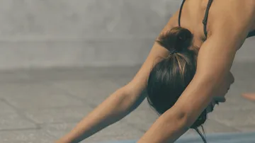 Person streckt sich auf Yogamatte drinnen.