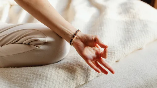Seated person meditating on a cushion.
