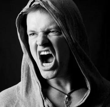 Person shouting in hoodie, dark background.