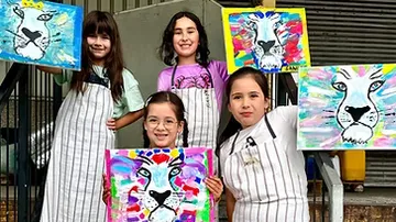Four children showing colorful lion paintings.