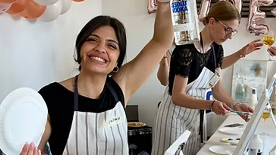 Woman smiling, holding vodka bottle, art class.