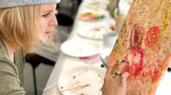 Woman painting on canvas at table.