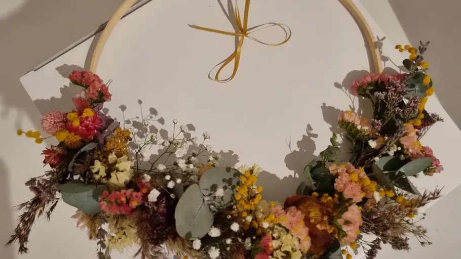 Blumenkranz auf weißem Untergrund, mit Band gebunden.