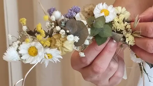 Hände arrangieren bunten Trockenblumenkranz.