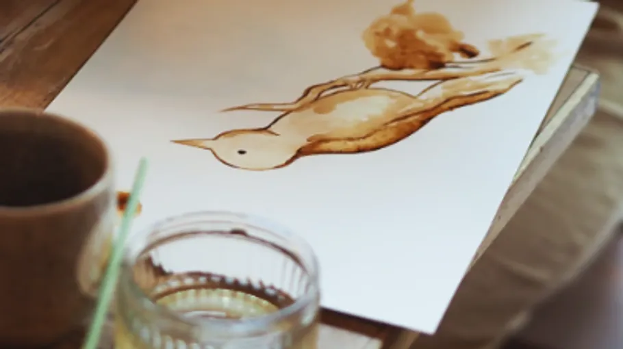 Vogel auf Papier gemalt, Kaffeetasse daneben.