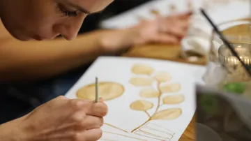 Person painting leaves with brush indoors.