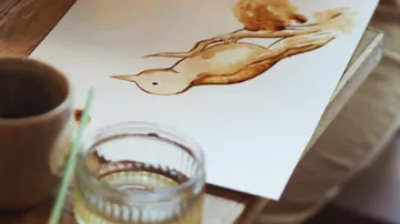 Watercolor bird painting on wooden table.