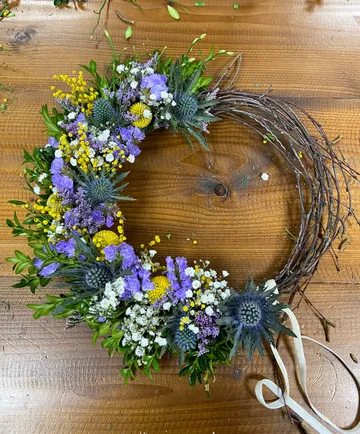 Floral wreath with colorful flowers on wood surface.