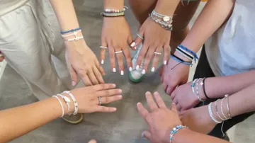 Group of hands wearing friendship bracelets.