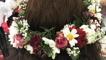 Floral crown on brown hair, indoor background.