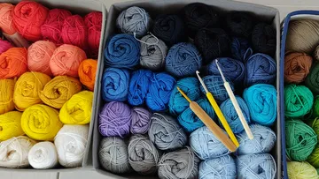 Bunte Garnknäuel mit Häkelnadeln.