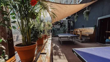 Outdoor ping pong tables under a shaded canopy.